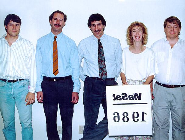 Founders Mark Dankberg, 史蒂夫·哈特和马克·米勒加上两名BET8十年信誉玩家首选网址的员工站在一个写着“Viasat 1986”的牌子后面