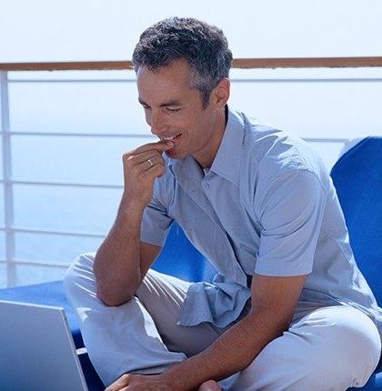 一名男子坐在一艘客轮的甲板上，用笔记本电脑与卫星网络的船