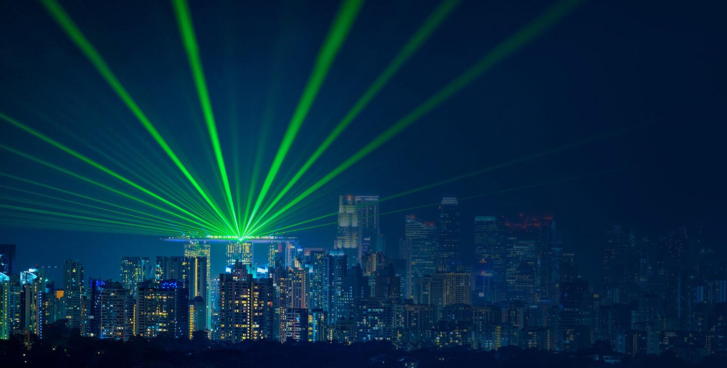 View of the city skyline with bright green lights beaming out from a building